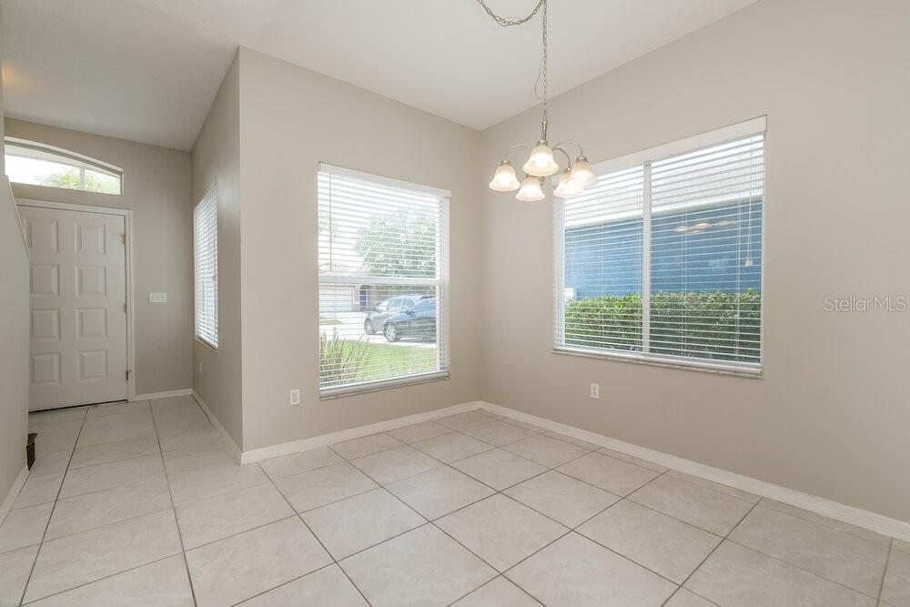 A dining area with light-colored tile flooring, a chandelier, and two windows — 13516 PRESTWICK DRIVE, RIVERVIEW, FL