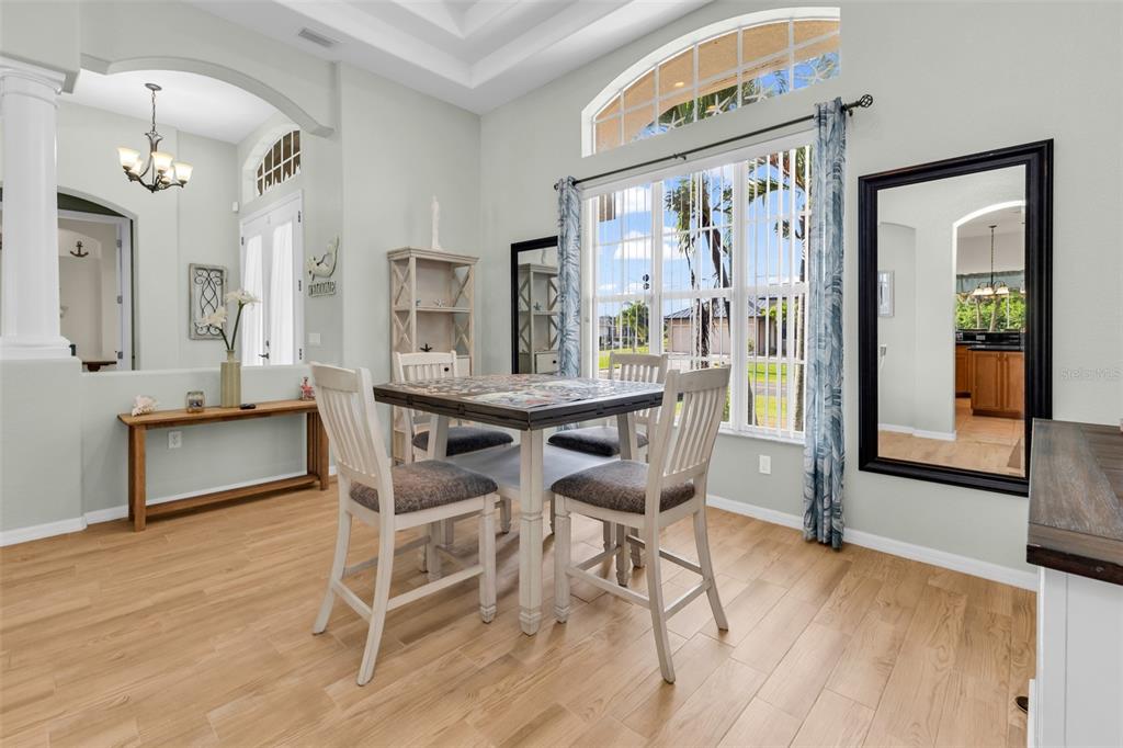 A dining area features a square table with four chairs, light wood floors, and large windows — 1146 ROTONDA CIRCLE, ROTONDA WEST, FL
