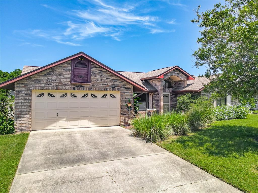 A single-story brick house with a two-car garage and a concrete driveway — 209 MEADOW LAKE DRIVE, EDGEWATER, FL