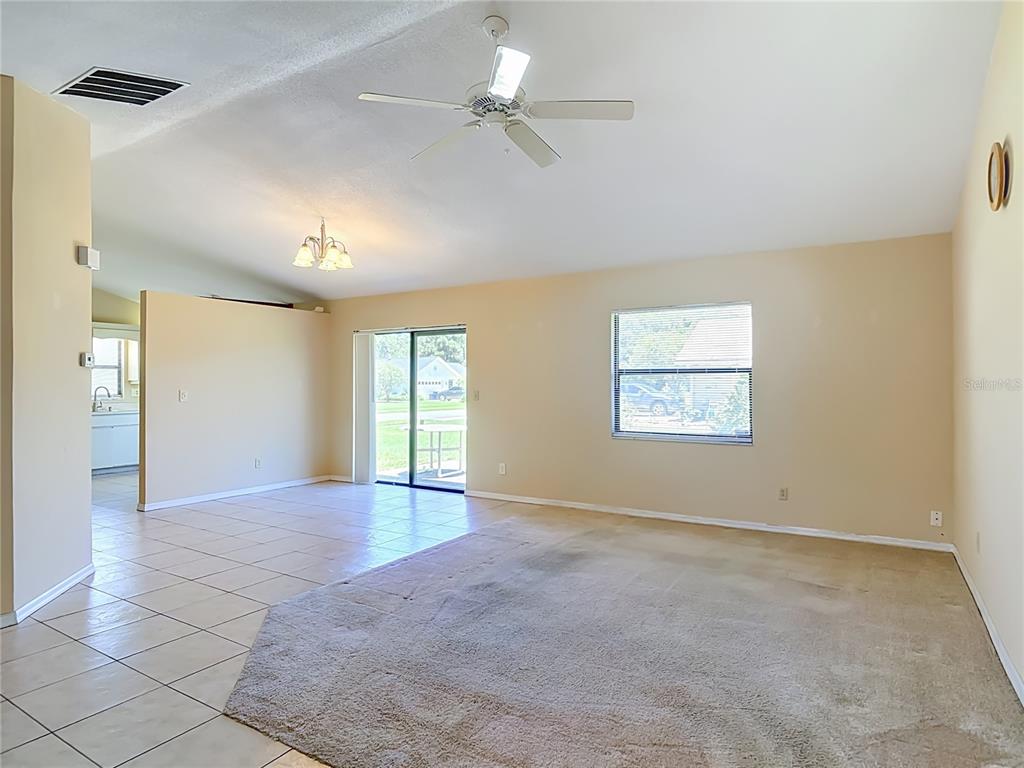 A living room features a mix of tile and carpet flooring, a ceiling fan, and windows — 209 MEADOW LAKE DRIVE, EDGEWATER, FL