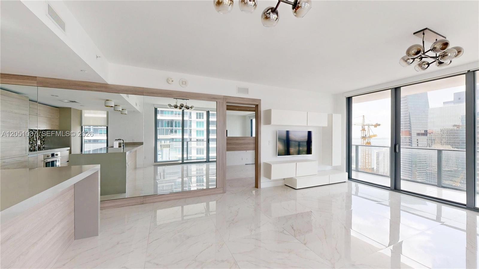 A modern living room features white marble floors, a wall-mounted television, and floor-to-ceiling windows — 1300 S Miami Ave # 3106, Miami FL 33130, MIAMI, FL