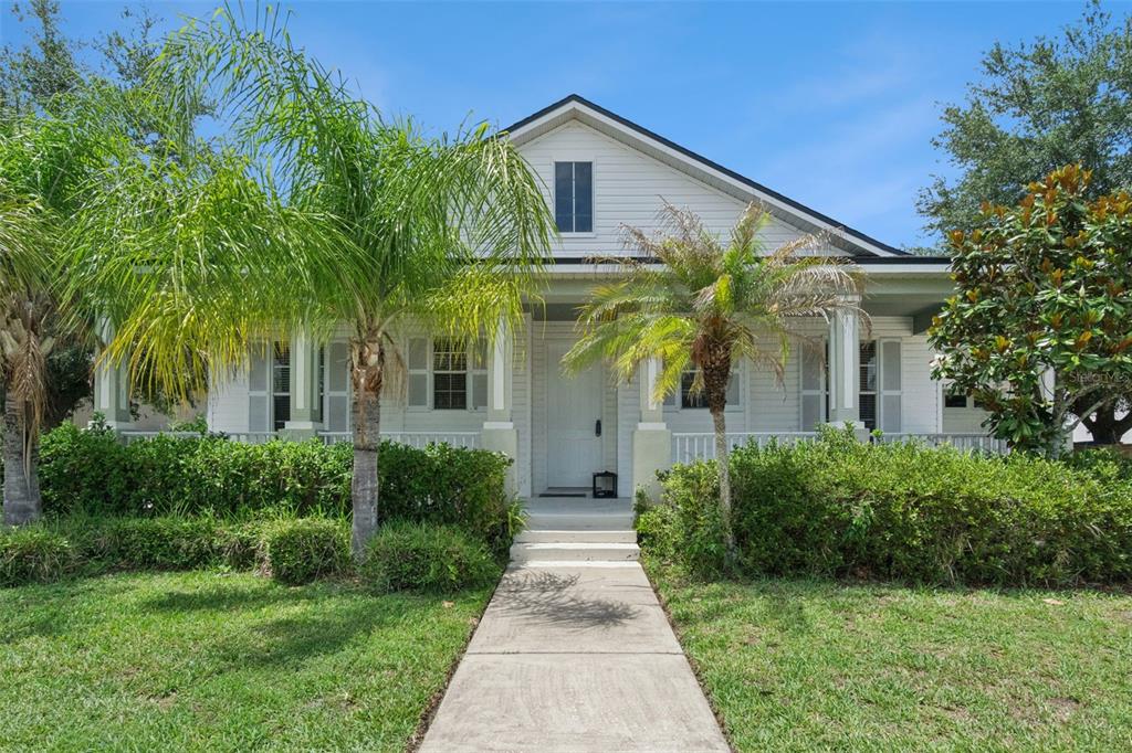 A white house with a front porch, palm trees, and a concrete walkway — 4957 PALL MALL STREET E, KISSIMMEE, FL