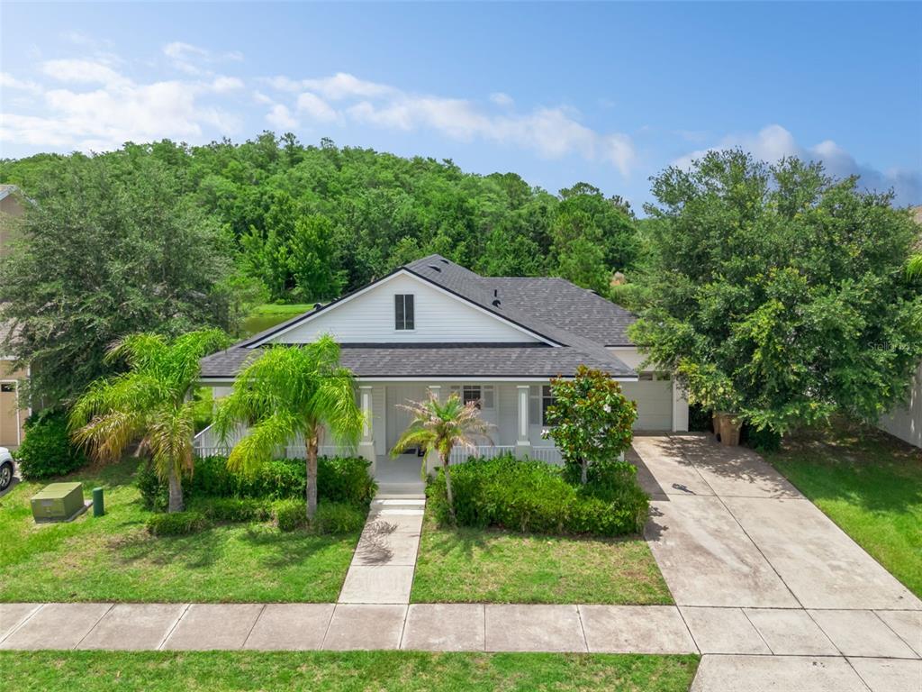 A single-story house with a white exterior, dark roof, and front porch faces a street — 4957 PALL MALL STREET E, KISSIMMEE, FL