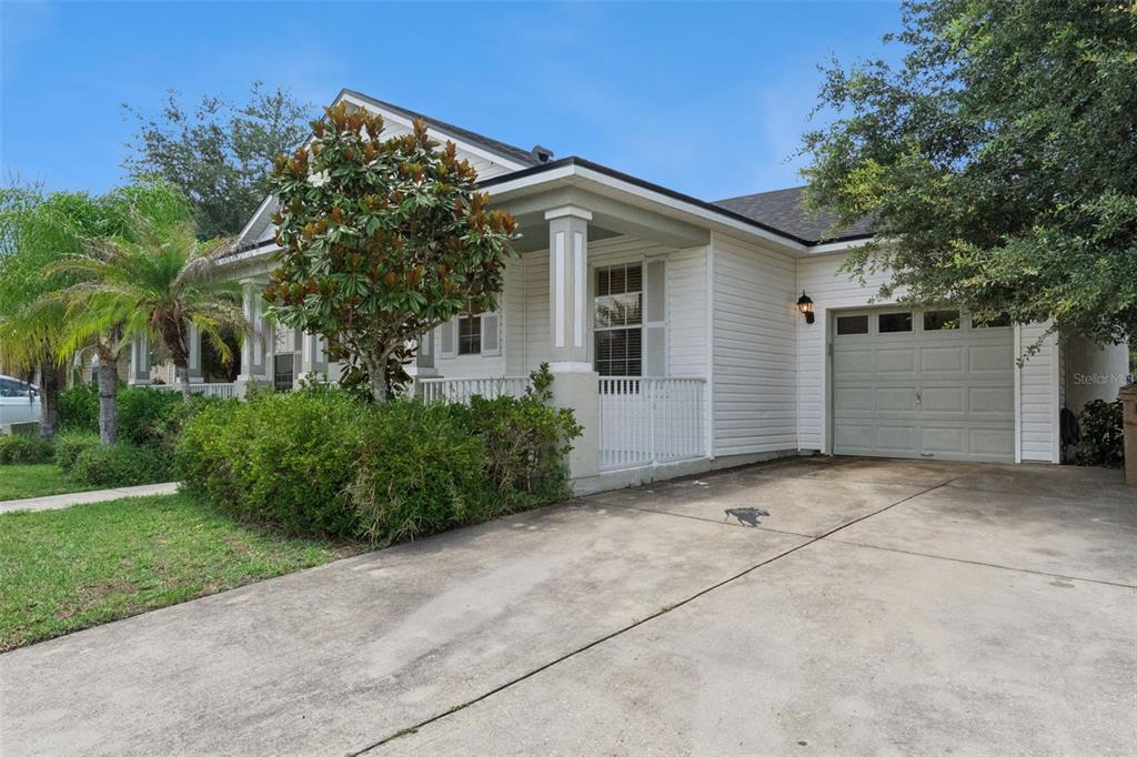 A white house with a front porch, a single-car garage, and a concrete driveway — 4957 PALL MALL STREET E, KISSIMMEE, FL