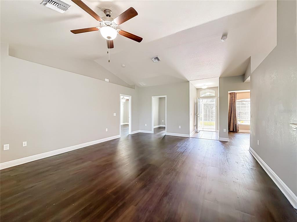 A spacious living room features dark wood flooring, a vaulted ceiling, and a ceiling fan — 1741 SHEVLIN STREET, NORTH PORT, FL