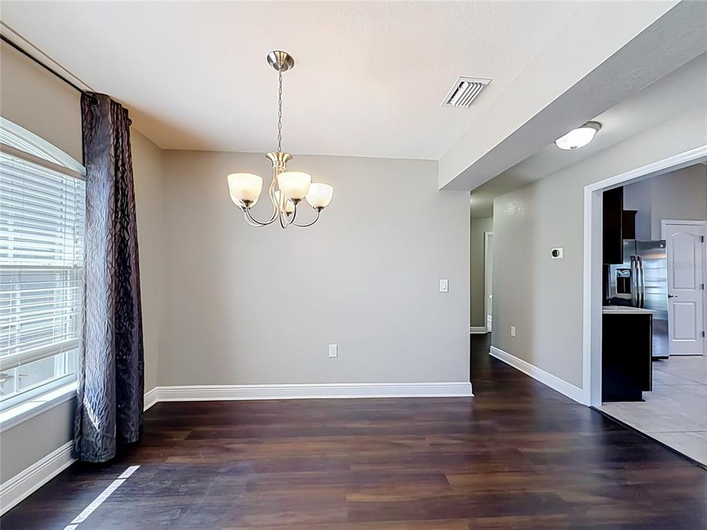 A dining area features dark wood flooring, a chandelier, and a view into a kitchen — 1741 SHEVLIN STREET, NORTH PORT, FL