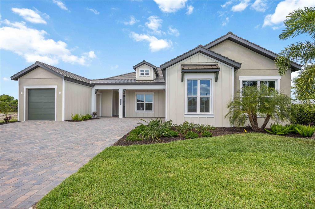 A single-story house with a paved driveway, a garage, and light-colored vertical siding — 18185 HOME RUN DRIVE, VENICE, FL