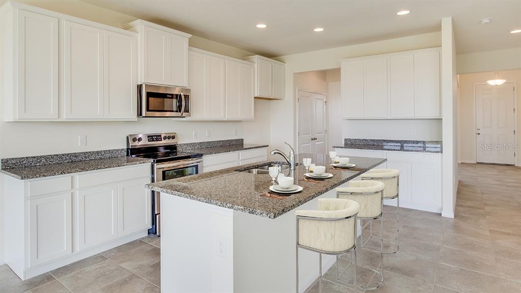 A kitchen with white cabinets, granite countertops, a center island, and stainless steel appliances — 17473 MAPLE GROVE ROAD, LAND O LAKES, FL