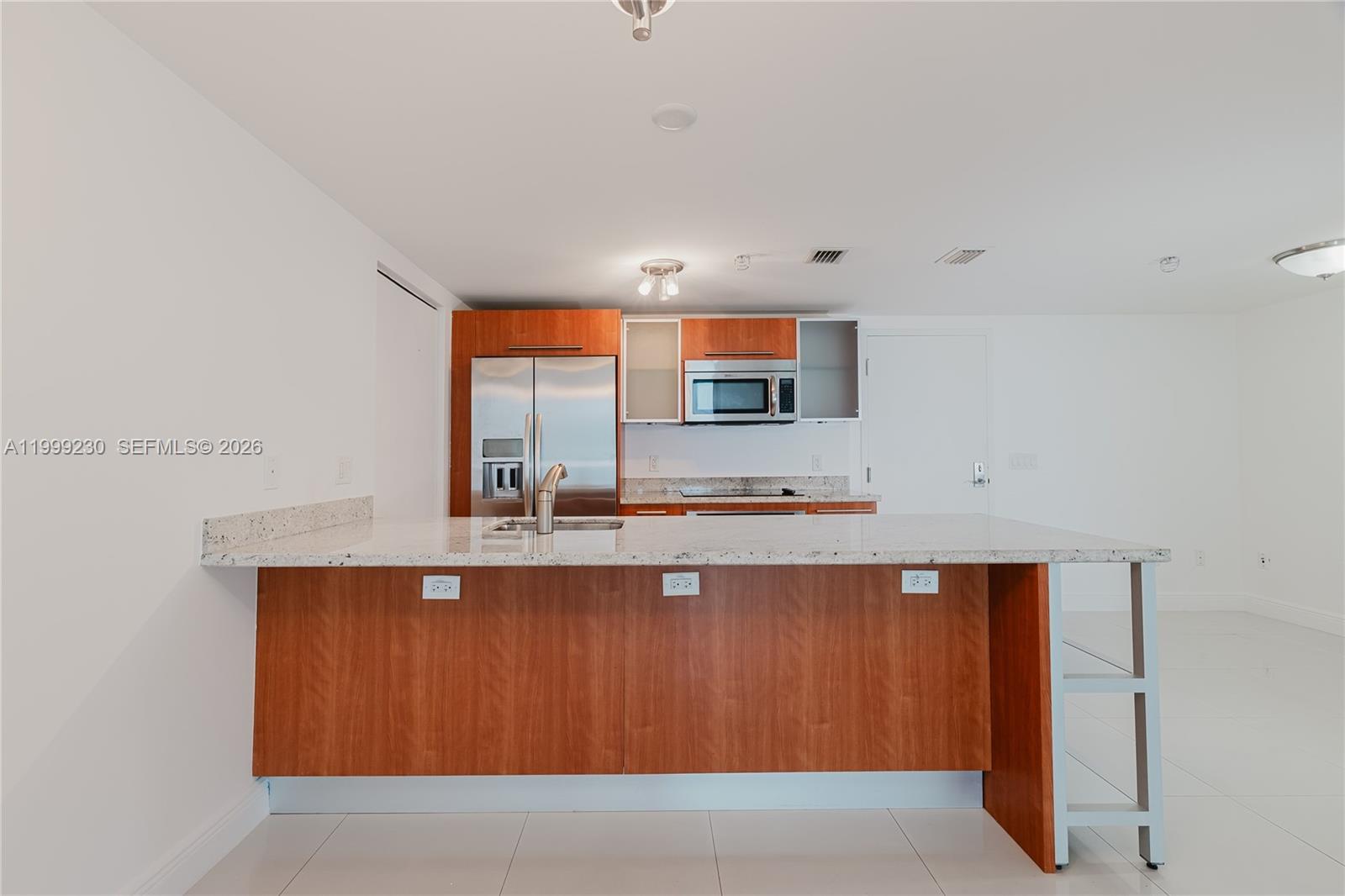 A kitchen features wood cabinets, stainless steel appliances, and a granite-topped island with outlets — 185 SW 7th St # 2007, Miami FL 33130, MIAMI, FL