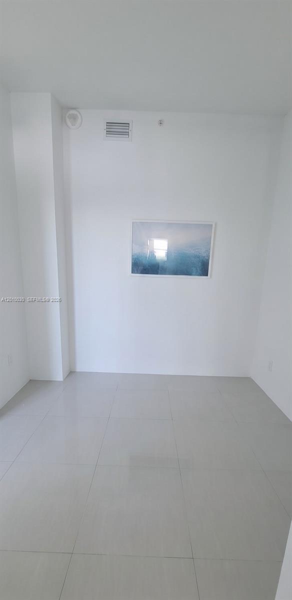 A minimalist room features white walls, light-colored tile flooring, and a framed ocean print — 2829 Indian Creek Dr # 1405, Miami Beach FL 33140, MIAMI BEACH, FL