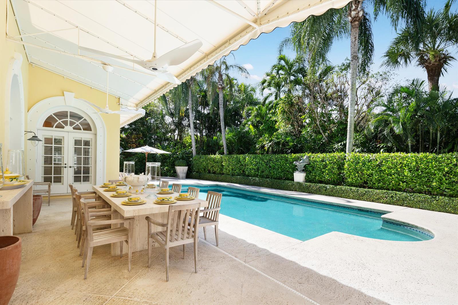 An outdoor dining area with a long stone table sits beside a rectangular swimming pool — 510 N Lake Way, Palm Beach FL 33480, PALM BEACH, FL
