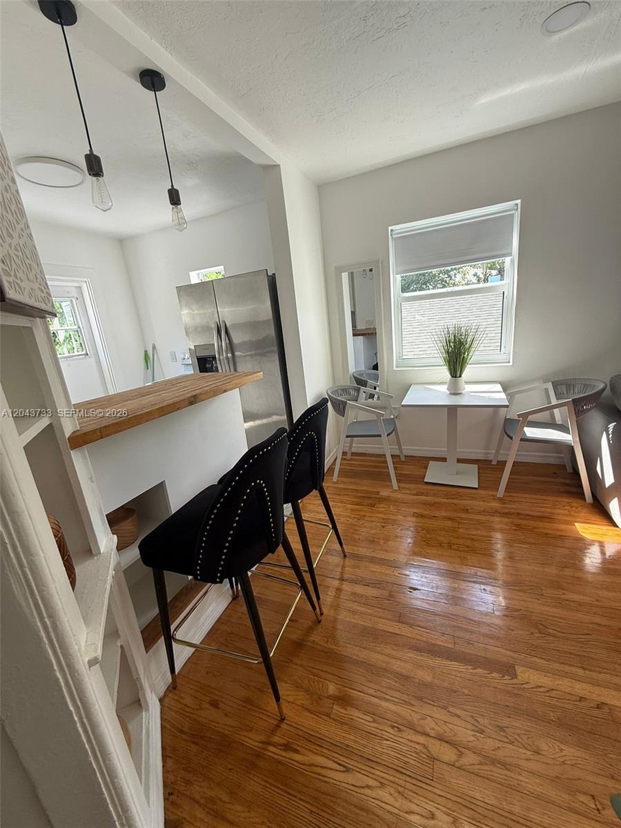 A kitchen features a breakfast bar with two black stools and a small dining area — 528 NE 70th St, Miami FL 33138, MIAMI, FL