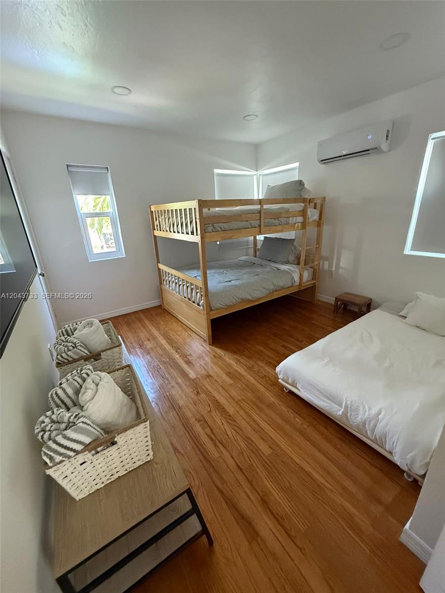A bedroom features hardwood floors, a wooden bunk bed, and a separate low-profile bed — 528 NE 70th St, Miami FL 33138, MIAMI, FL