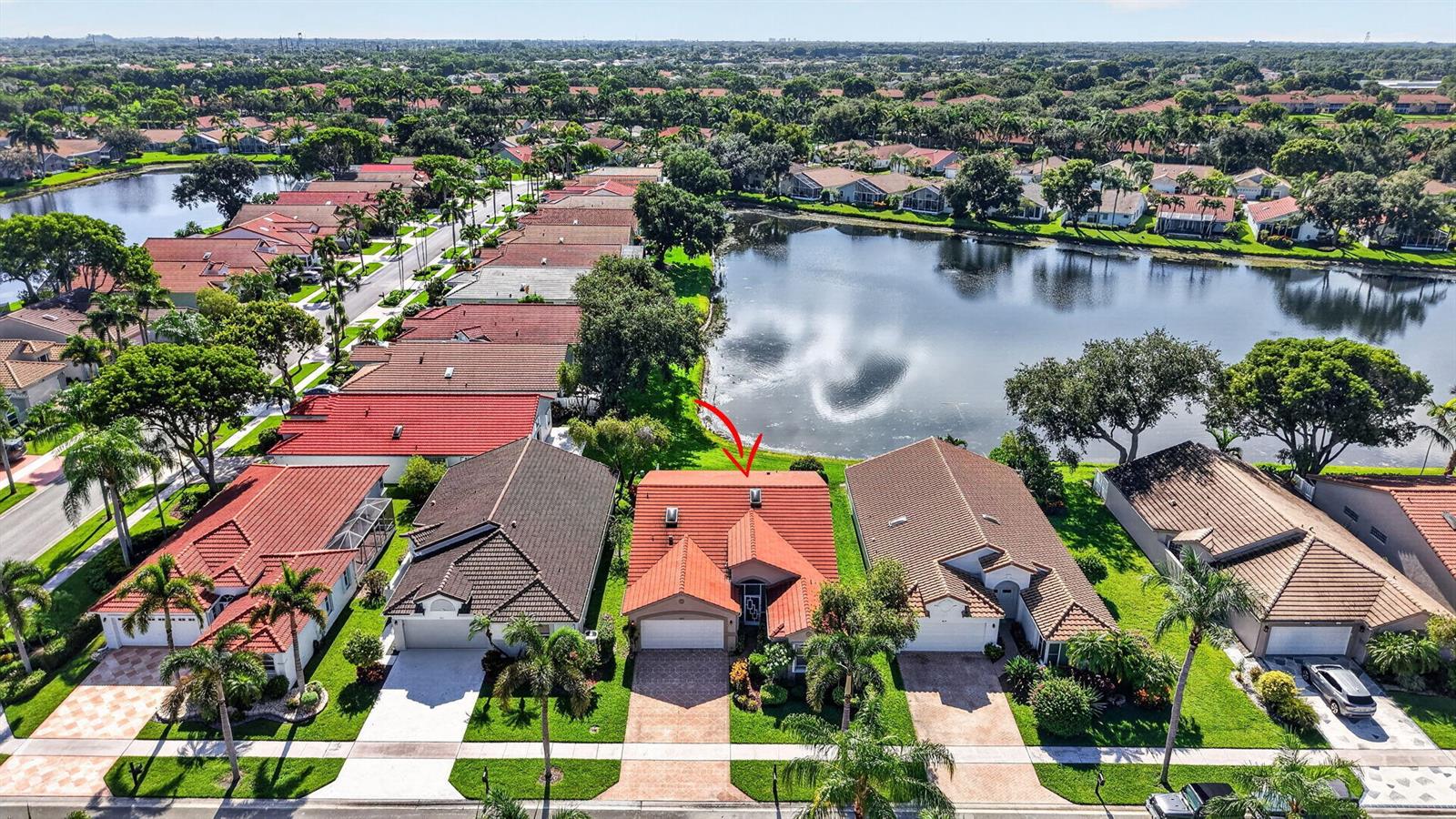An aerial view shows a suburban house with a red tile roof beside a lake — 9875 Harbour Lake Circle, Boynton Beach FL 33437, BOYNTON BEACH, FL