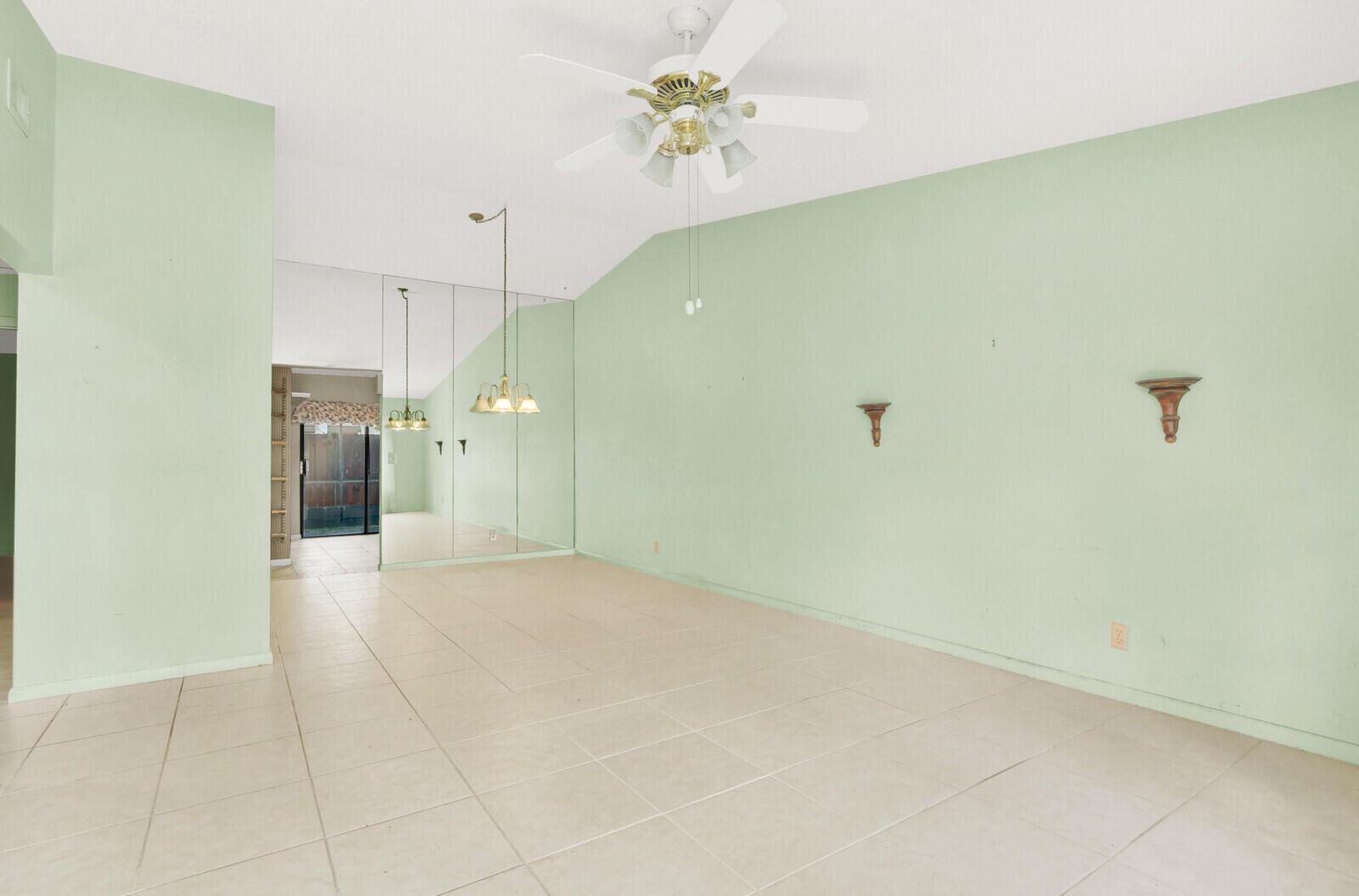 An empty room with light green walls, tiled floors, a ceiling fan, and mirrored walls — 8091 SE Villa Circle, Hobe Sound FL 33455, HOBE SOUND, FL
