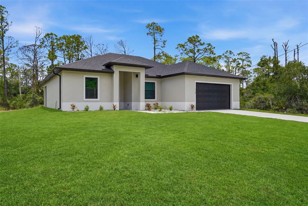 A single-story house with a beige stucco exterior, dark roof, and a two-car garage — 1113 SHERWIN STREET, PORT CHARLOTTE, FL