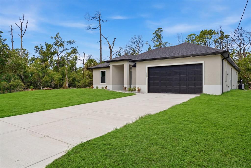 A single-story house with a dark garage door and a concrete driveway sits on grass — 1113 SHERWIN STREET, PORT CHARLOTTE, FL