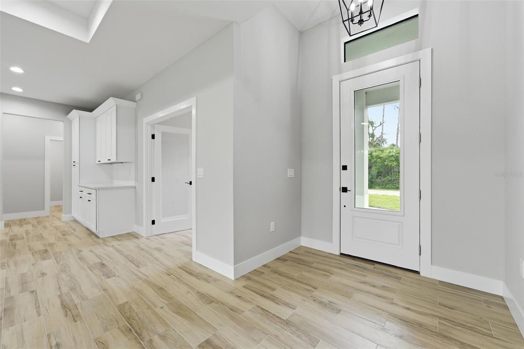 A bright entryway with light wood-look tile flooring, white walls, and a glass-paneled front door — 1113 SHERWIN STREET, PORT CHARLOTTE, FL
