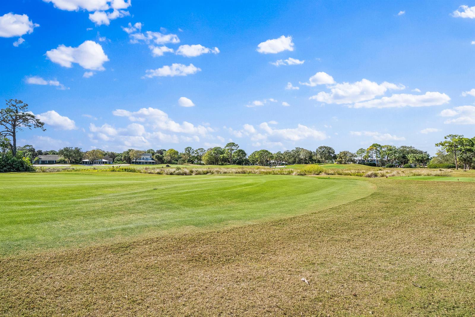 A view of a green golf course fairway under a bright blue sky with clouds — 747 Hampton Woods Lane SW, Vero Beach FL 32962, VERO BEACH, FL