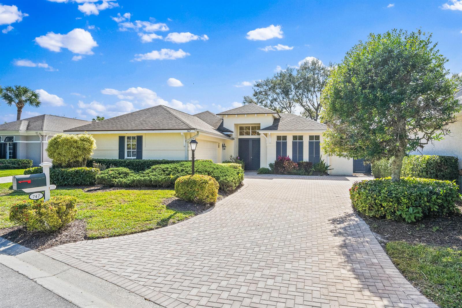 A single-story house with a paved driveway, a front lawn, and dark-framed windows — 747 Hampton Woods Lane SW, Vero Beach FL 32962, VERO BEACH, FL