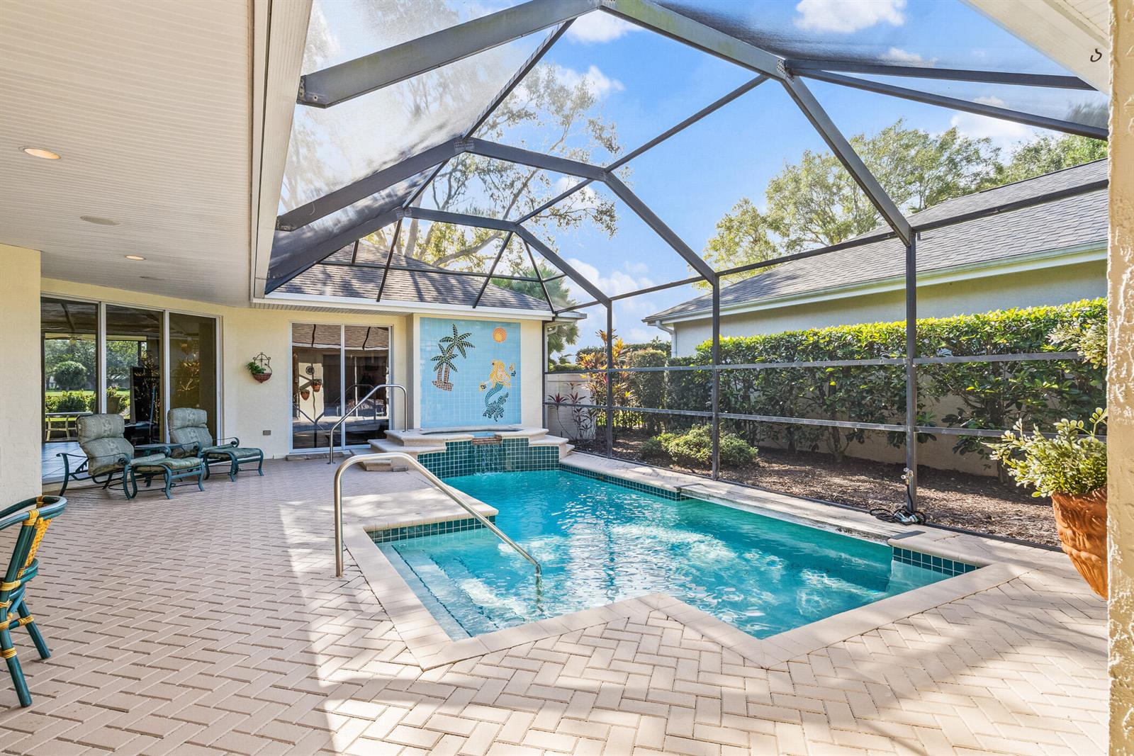 A screened-in patio features a small swimming pool with a tiled mermaid mural wall — 747 Hampton Woods Lane SW, Vero Beach FL 32962, VERO BEACH, FL