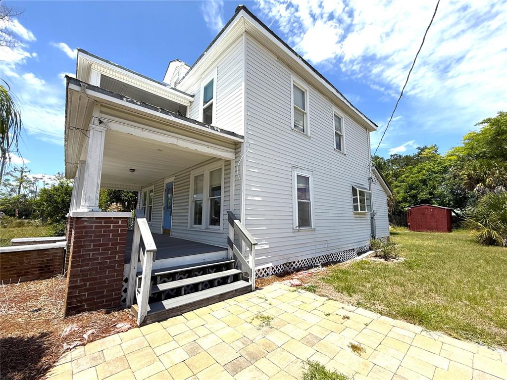 A two-story house with light gray siding, a brick-based porch, and a paved patio — 214 W WHIDDEN STREET, ARCADIA, FL