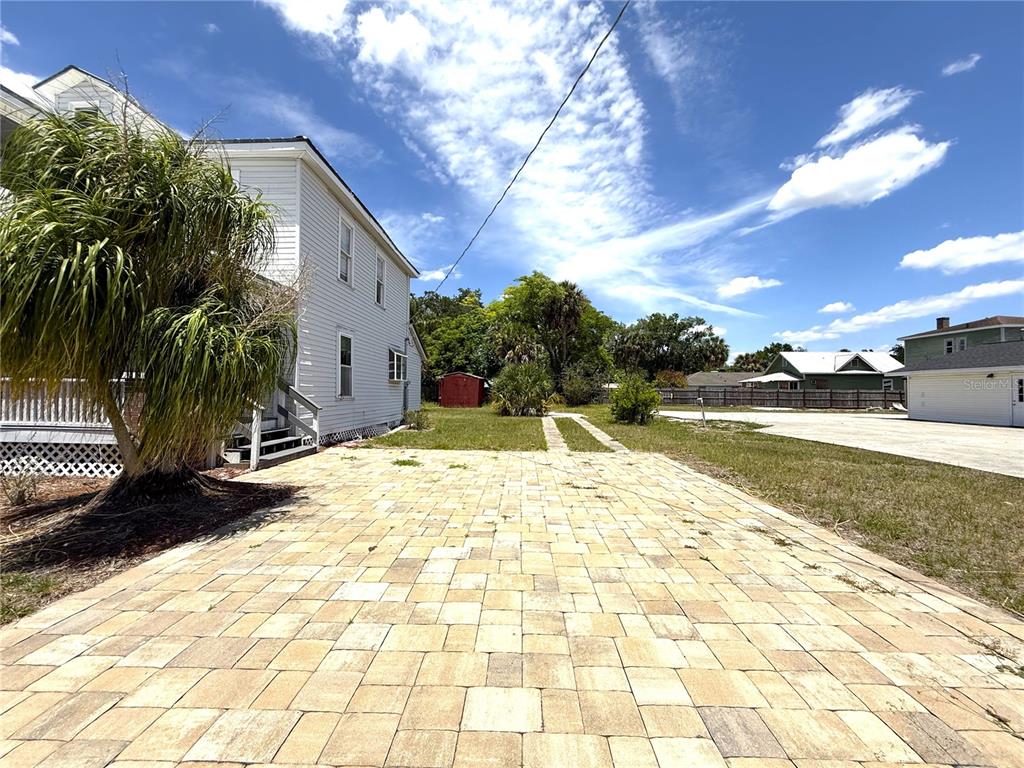 A paved driveway leads toward a white house with a palm tree and shed — 214 W WHIDDEN STREET, ARCADIA, FL