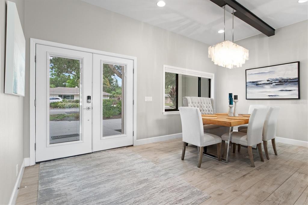 A dining area with a wood table, upholstered chairs, a chandelier, and double glass doors — 1905 TULIP DRIVE, SARASOTA, FL