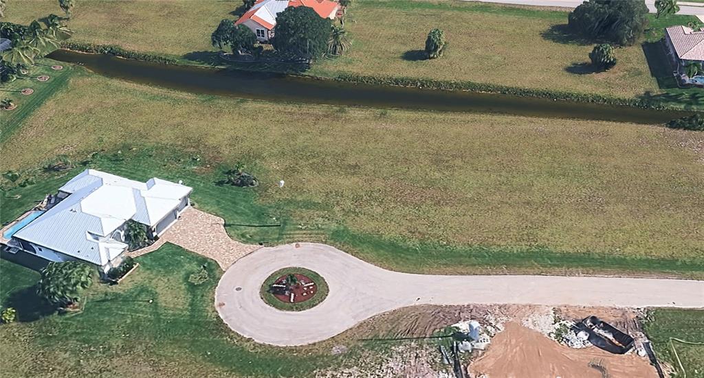 An aerial view shows a house with a circular driveway and a canal behind it — 17254 TAMPICO LANE, PUNTA GORDA, FL