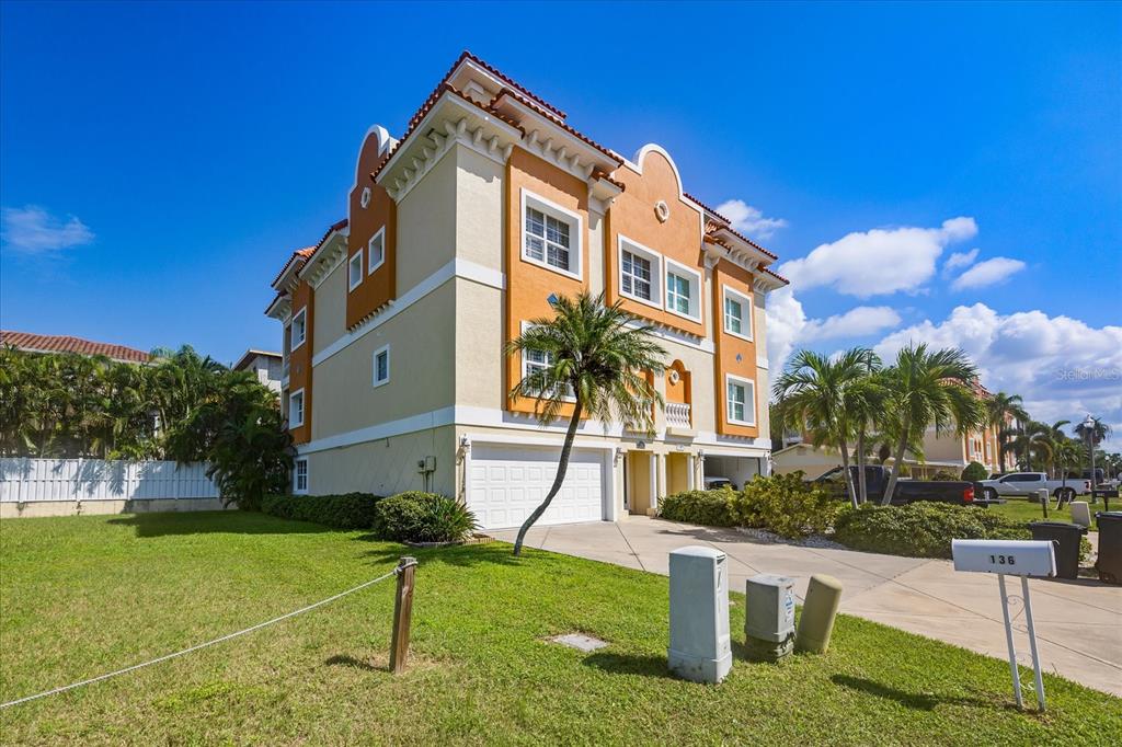 A three-story stucco townhouse with a two-car garage and a palm tree in front — 136 175TH AVENUE E, REDINGTON SHORES, FL
