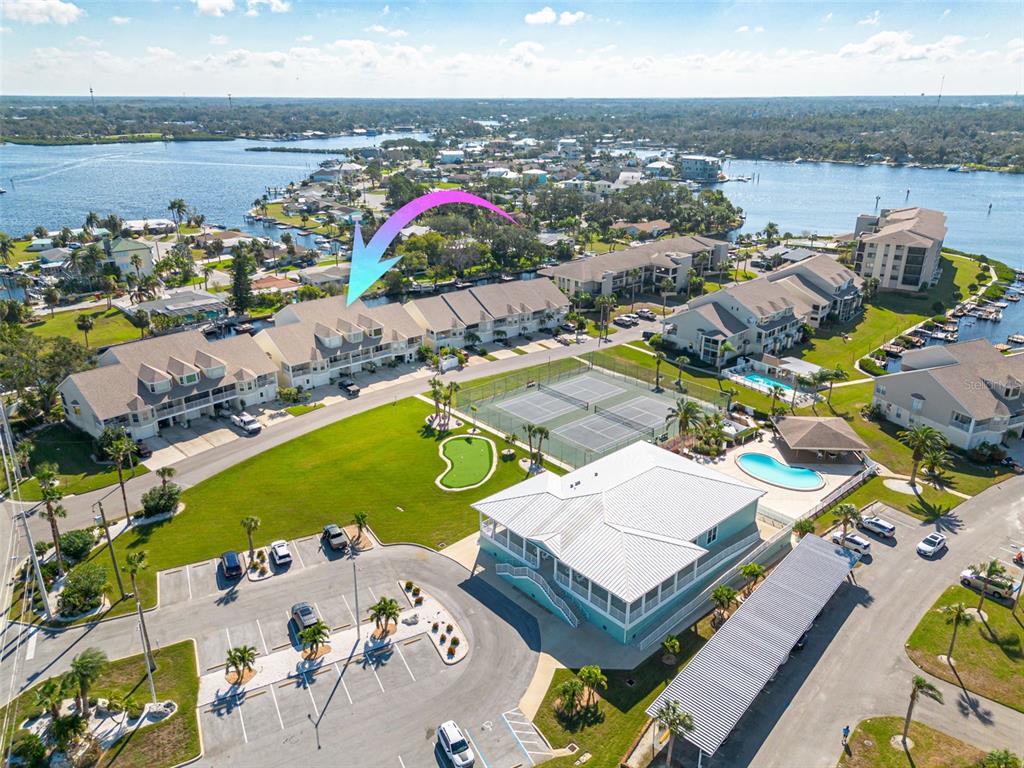 An aerial view shows a multi-story residential complex with tennis courts, a pool, and parking — 8246 AQUILA STREET, PORT RICHEY, FL