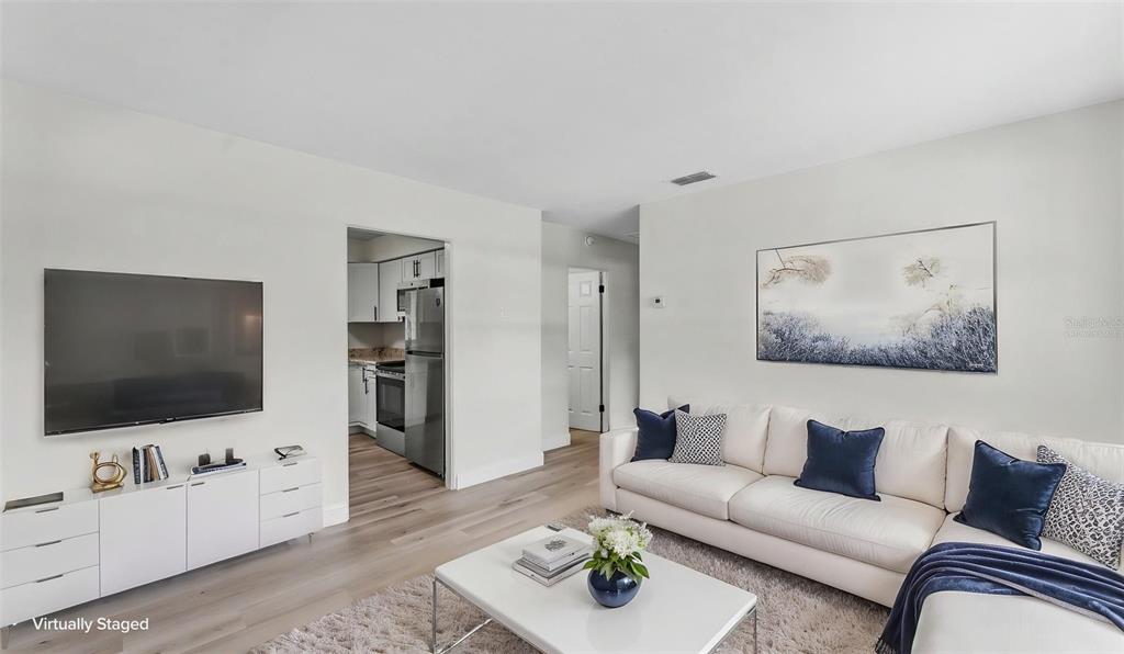 A living room features a white sectional sofa, a television, and light wood flooring — 1725 31ST STREET NW, WINTER HAVEN, FL