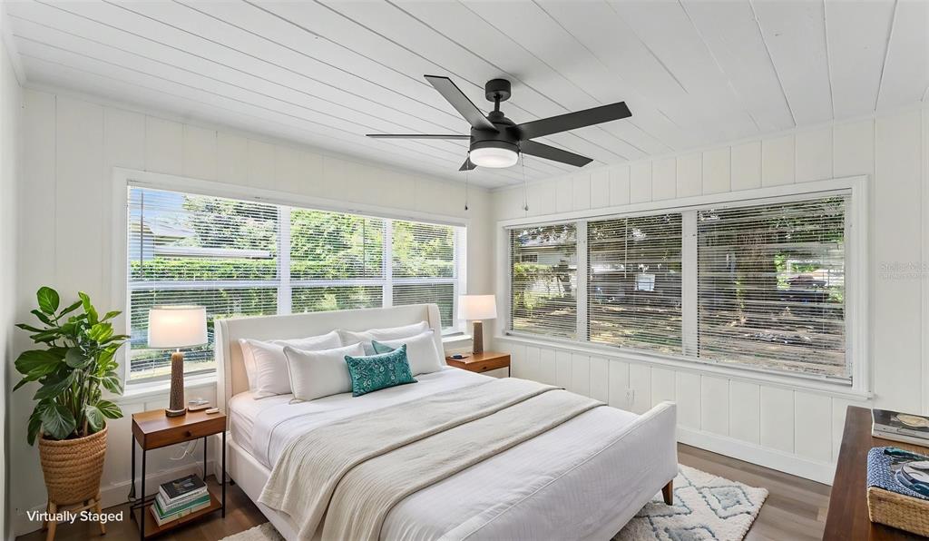 A bedroom with white paneled walls, a ceiling fan, and windows overlooking a yard — 1725 31ST STREET NW, WINTER HAVEN, FL