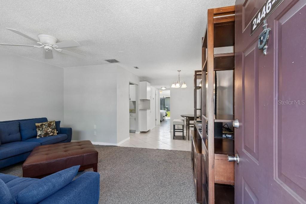 A living room with blue sofas, carpeted flooring, and an open view into the kitchen — 2446 ENTERPRISE ROAD UNIT 4, CLEARWATER, FL