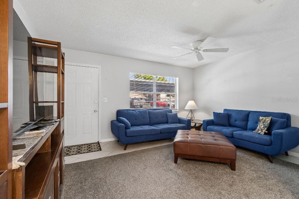 A living room features two blue sofas, a leather ottoman, and a ceiling fan — 2446 ENTERPRISE ROAD UNIT 4, CLEARWATER, FL