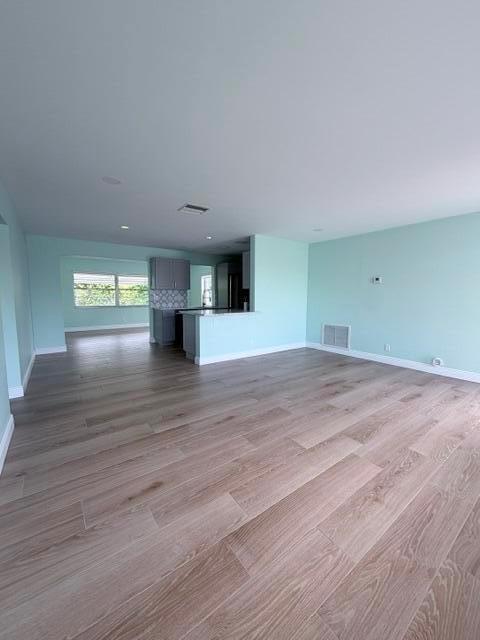 An open-concept living area features light wood-look flooring and pale blue walls — 1308 SW 24th Street, Boynton Beach FL 33426, BOYNTON BEACH, FL