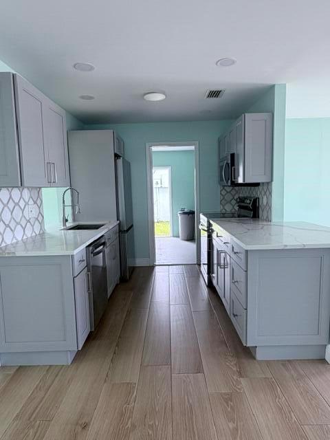 A kitchen features light gray cabinets, white countertops, and wood-look tile flooring — 1308 SW 24th Street, Boynton Beach FL 33426, BOYNTON BEACH, FL