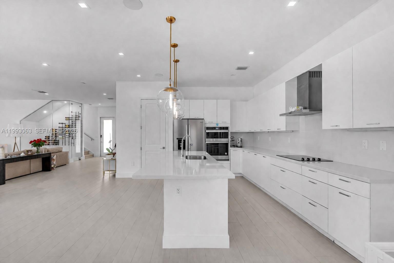 A modern white kitchen features a central island, stainless steel appliances, and light wood flooring — 8019 NW 46th Ter, Doral FL 33166, DORAL, FL