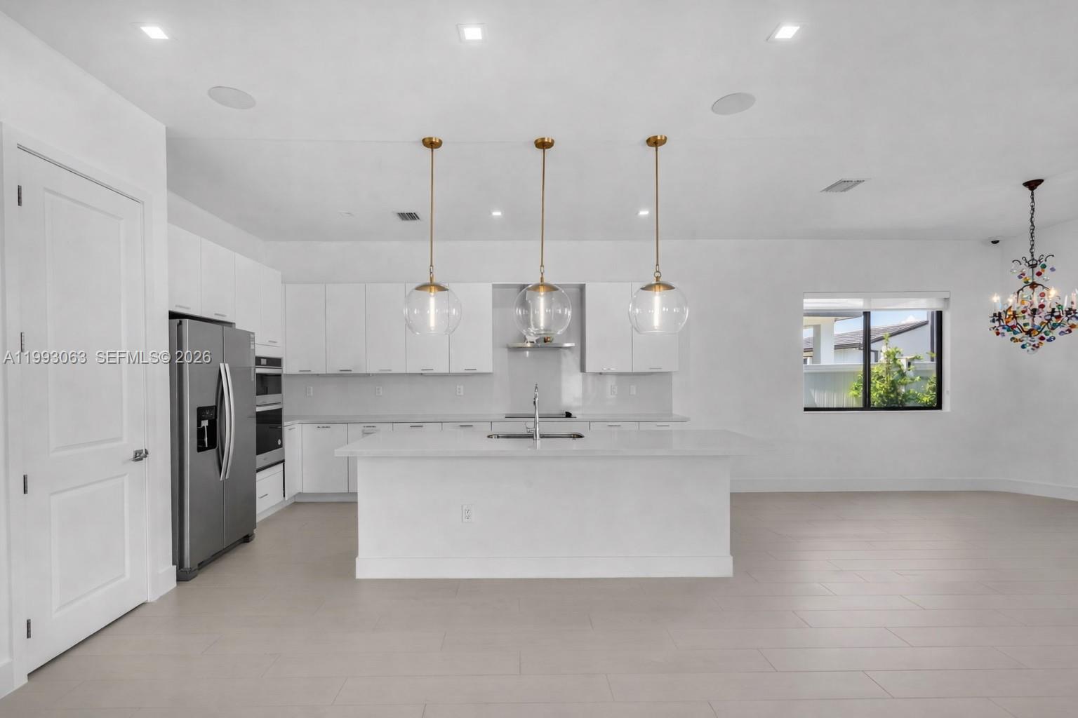 A modern white kitchen features a central island, stainless steel appliances, and three pendant lights — 8019 NW 46th Ter, Doral FL 33166, DORAL, FL