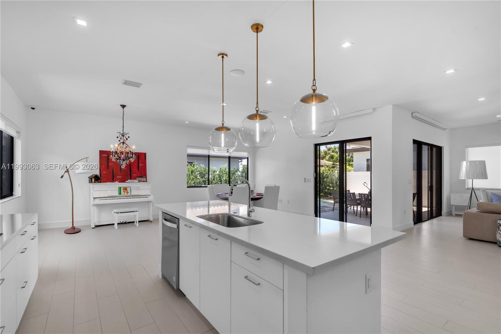 A modern kitchen features a white island with a sink, pendant lighting, and a piano — 8019 NW 46th Ter, Doral FL 33166, DORAL, FL