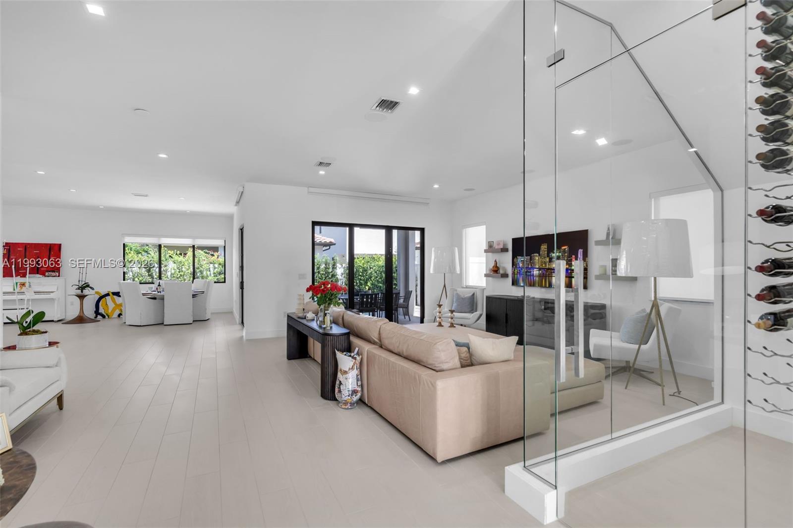 A bright, open-concept living room features a glass-enclosed wine display and modern neutral decor — 8019 NW 46th Ter, Doral FL 33166, DORAL, FL