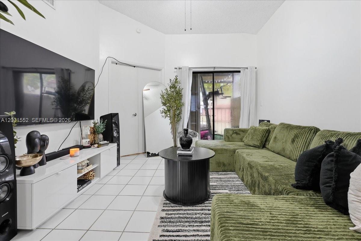 A living room features a green sectional sofa, a white media console, and tile flooring — 9839 SW 138th Ave, Miami FL 33186, MIAMI, FL