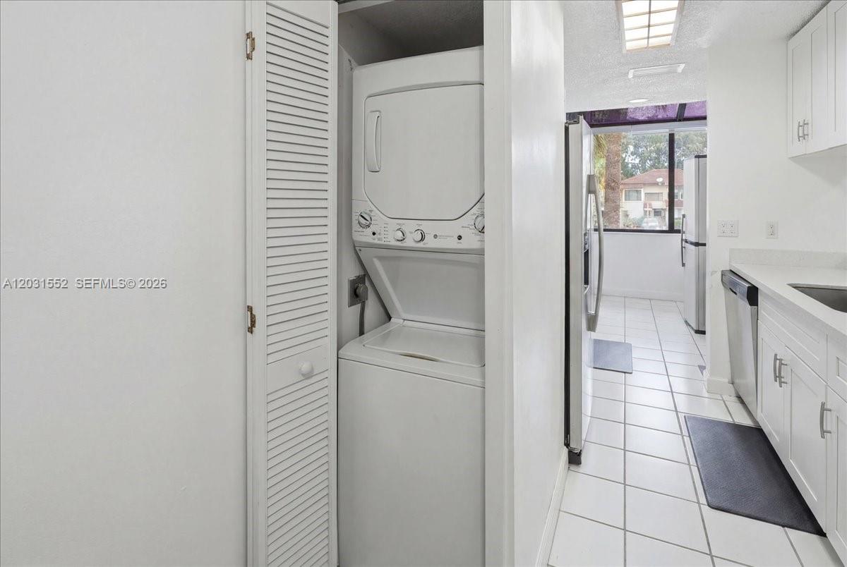 A stacked washer and dryer unit is located in a closet next to a kitchen — 9839 SW 138th Ave, Miami FL 33186, MIAMI, FL