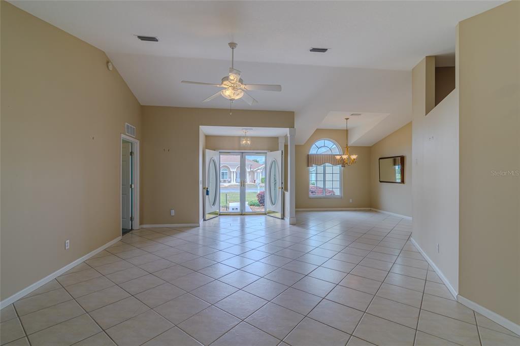 A spacious, tiled living area features a vaulted ceiling, ceiling fan, and double front doors — 2020 NW 50TH CIRCLE, OCALA, FL