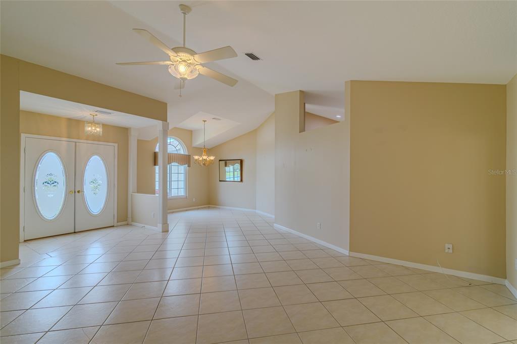 An open-concept living area features beige walls, light-colored tile flooring, and a ceiling fan — 2020 NW 50TH CIRCLE, OCALA, FL