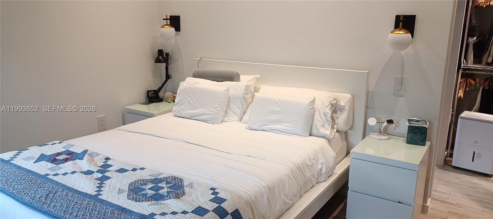 A bedroom features a white bed with a blue patterned quilt and two nightstands — 363 Washington Ave # 31, Miami Beach FL 33139, MIAMI BEACH, FL