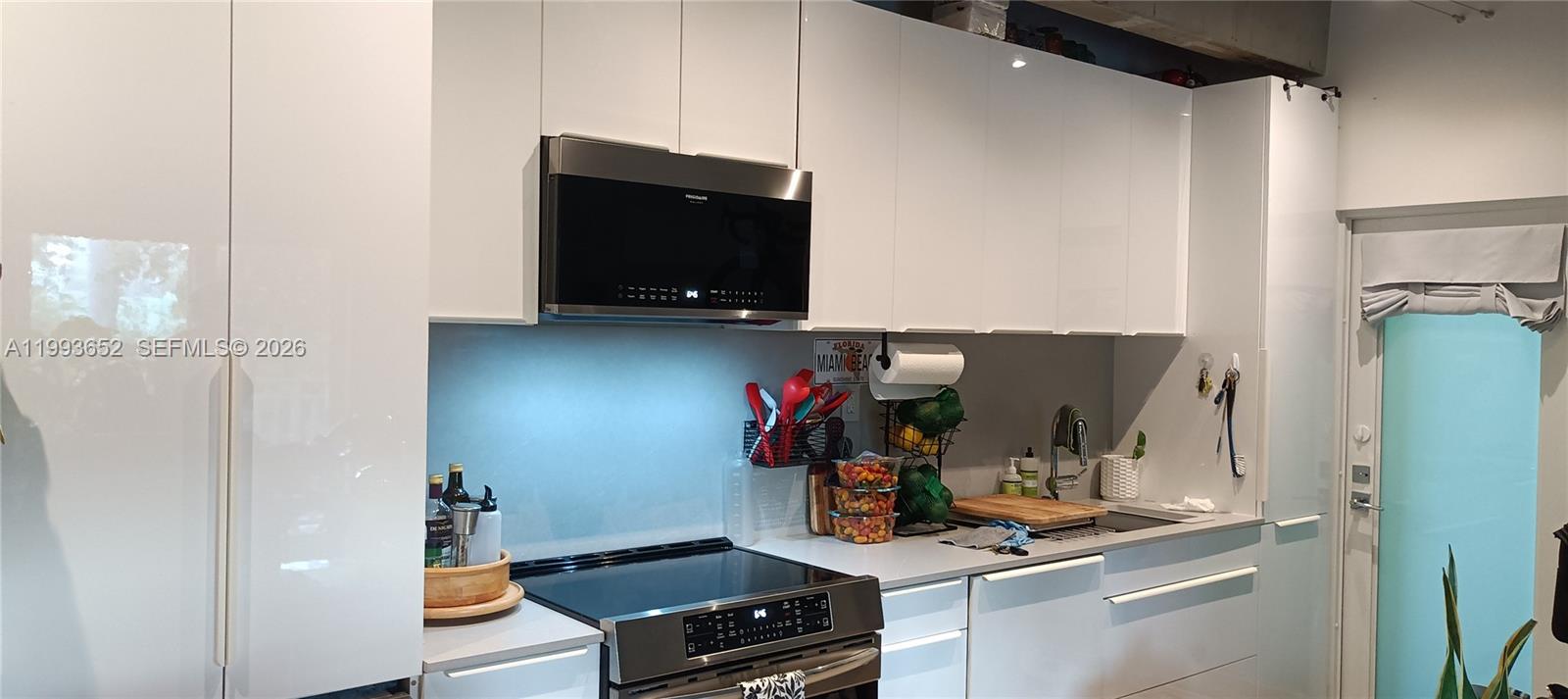A modern kitchen features white glossy cabinets, stainless steel appliances, and a light gray countertop — 363 Washington Ave # 31, Miami Beach FL 33139, MIAMI BEACH, FL