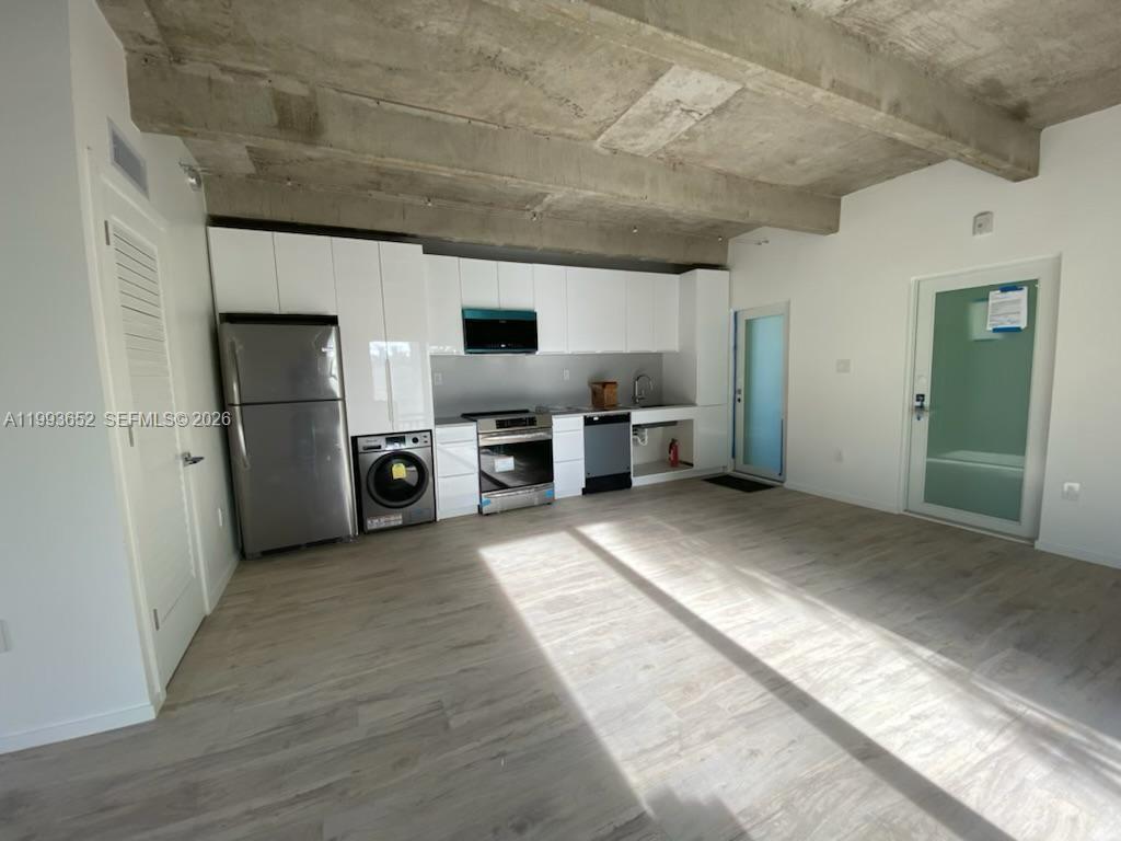 A modern kitchen features white cabinets, stainless steel appliances, and an exposed concrete ceiling — 363 Washington Ave # 31, Miami Beach FL 33139, MIAMI BEACH, FL