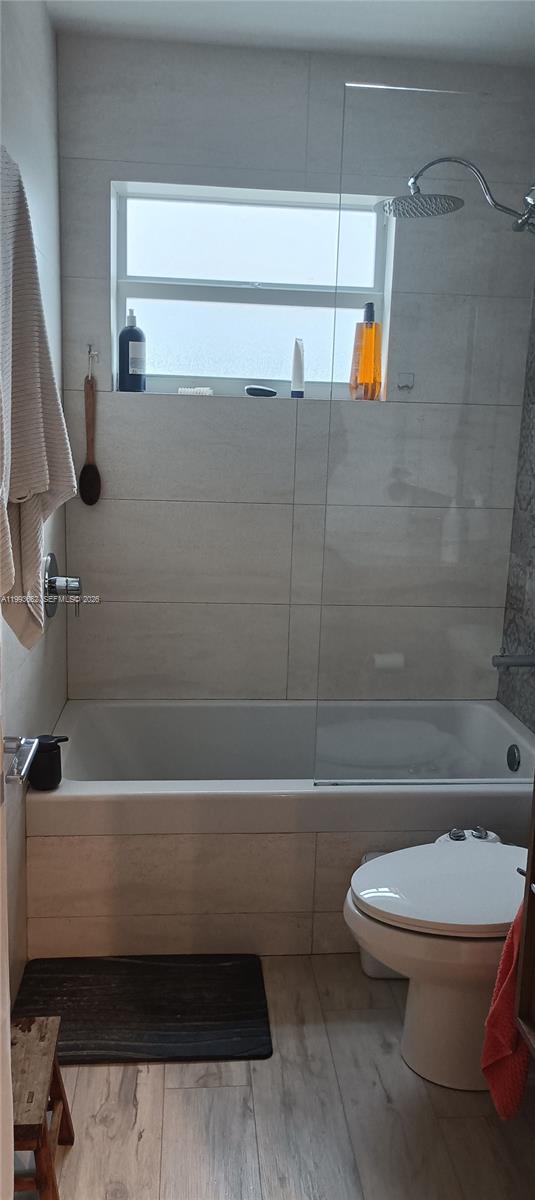 A bathroom features a bathtub with a glass shower panel, a toilet, and light-colored tiling — 363 Washington Ave # 31, Miami Beach FL 33139, MIAMI BEACH, FL