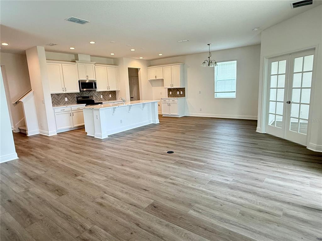 A kitchen with white cabinets and a center island opens into a spacious living area — 7497 CATANIA LOOP, CLERMONT, FL